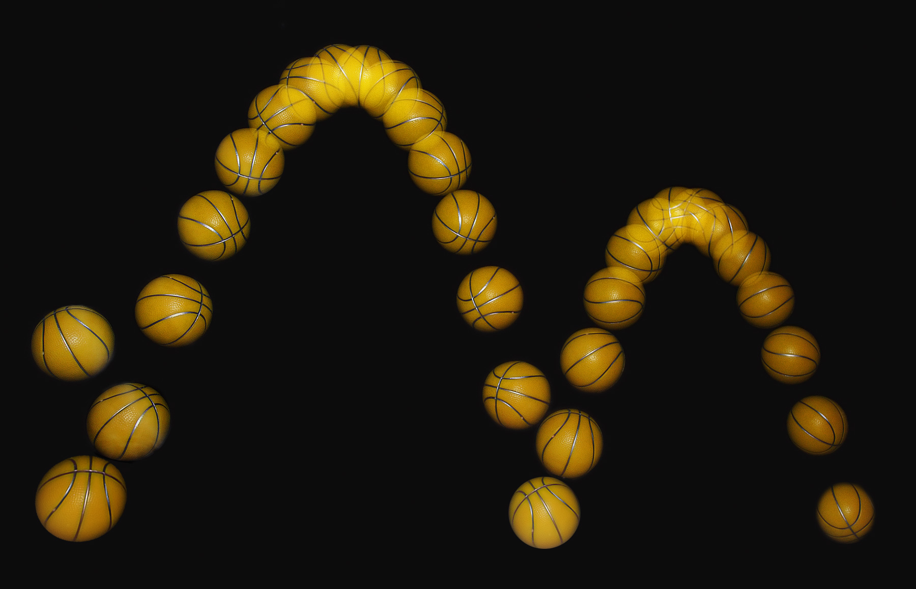 Successive positions of a small yellow ball falling and bouncing, photographed against a black background.