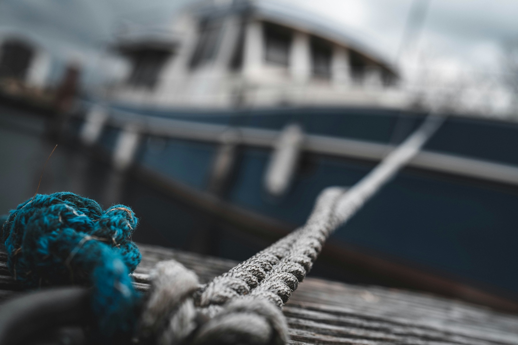 A thick rope stretches from a weathered dock toward a boat in the background